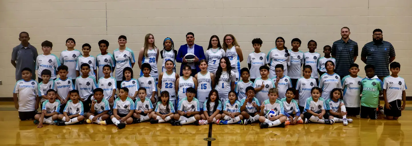 Children's basketball team posing together with coach in gym.