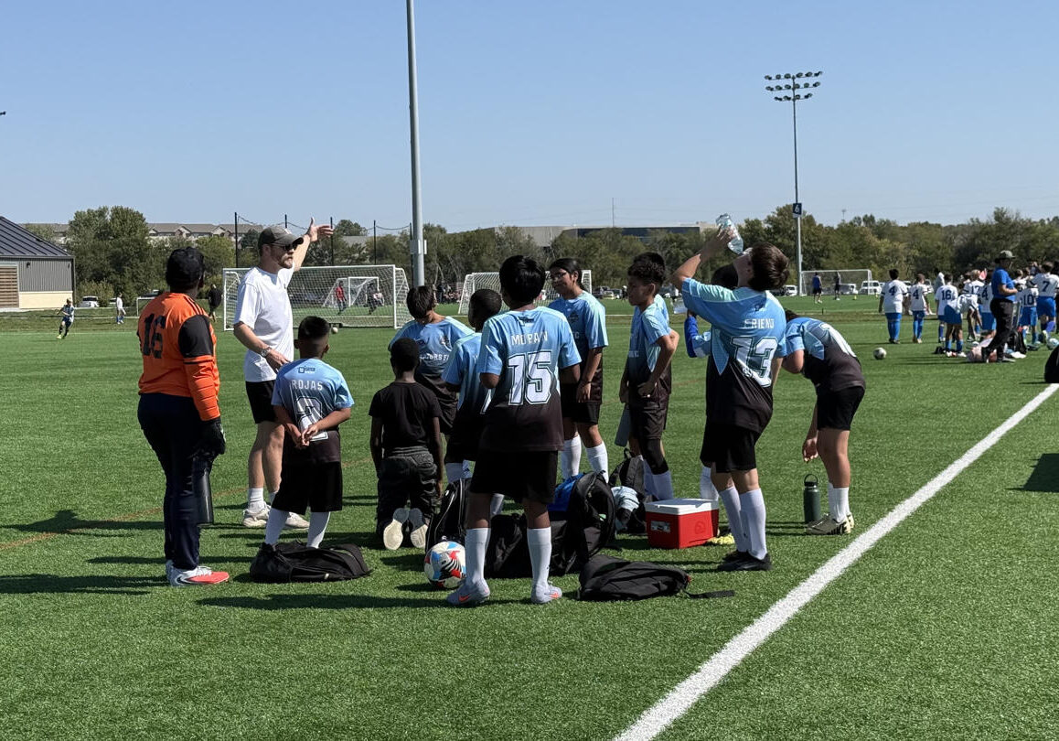 Youth football team gathered on the sidelines during a game.